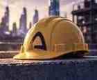 Yellow construction hard hat with black Arc A logo on concrete, golden-hour city behind